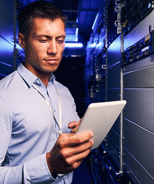 Waist-up portrait of serious IT engineer consulting tablet computer during routine maintenance procedure